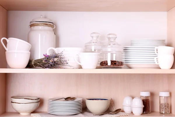 Utensilios de cocina y vajilla en estantes de madera —  Fotos de Stock