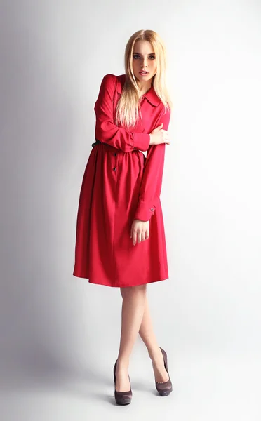Ekspresyjny młody model w czerwonej sukience na szarym tle — Zdjęcie stockowe
