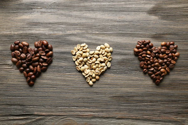 Koffie bonen in de vorm van harten op houten achtergrond — Stockfoto