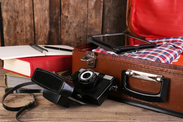 Packing suitcase for trip on wooden background — Stock Photo, Image