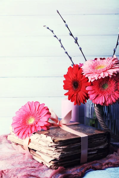 Schöne helle Gerberas in Vase mit alten Büchern auf Holzgrund — Stockfoto
