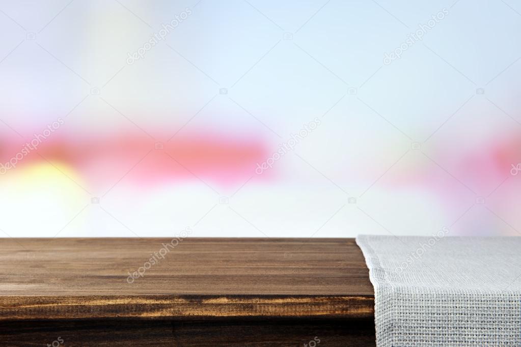 Empty wooden table with napkin and light background