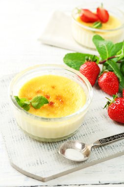 Creme brulee tatlı taze çilek ve renk ahşap zemin üzerine nane yaprakları ile