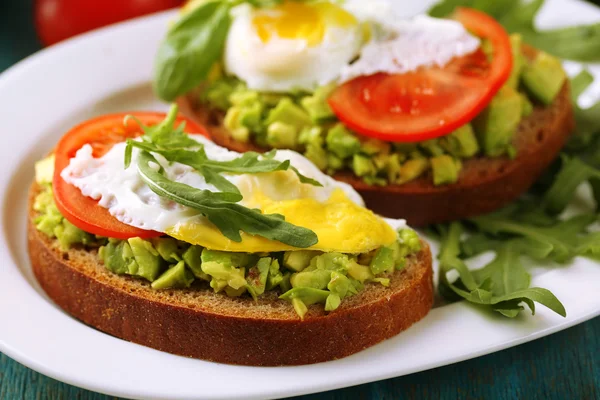 Tasty sandwiches with egg, avocado and vegetables on plate, on wooden background — Stock Photo, Image