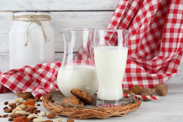 Latte in bicchieri con noci e biscotti su tavolo di legno con tovagliolo, primo piano — Foto Stock