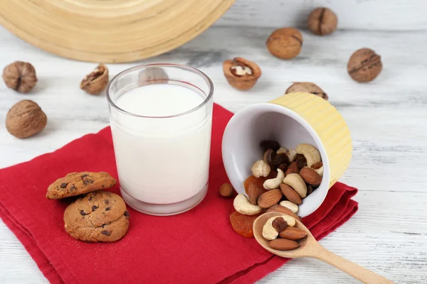 Milch im Glas mit Walnüssen und Keksen auf Holztisch, Nahaufnahme — Stockfoto