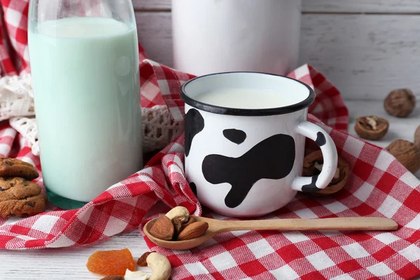 Milk in glassware with walnuts and cookies on wooden table with napkin, closeup — Stock Photo, Image