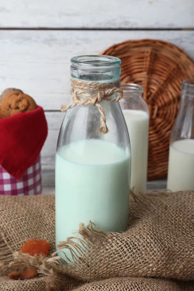 Latte in bicchieri e noci su tavola di legno con sacco, primo piano — Foto Stock