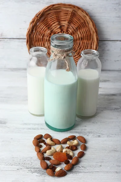 Leche en cristalería y nueces sobre fondo de madera —  Fotos de Stock