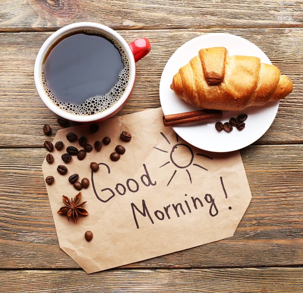 Tasse Kaffee mit frischem Croissant und Guten Morgen Massage auf Holztisch, Draufsicht — Stockfoto