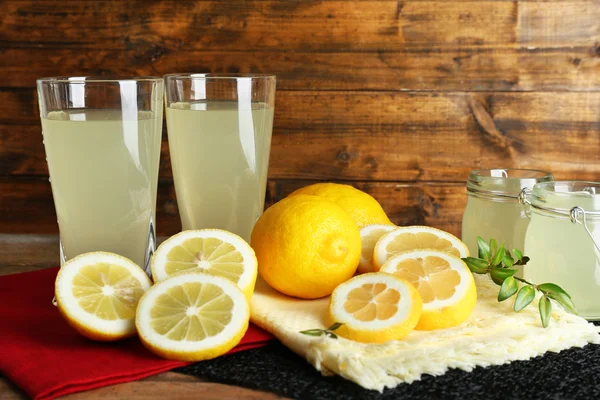 Bodegón con jugo de limón y limones en rodajas sobre fondo de madera — Foto de Stock