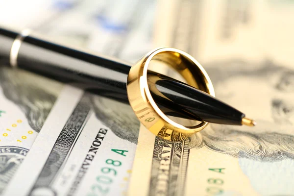 Обручальное кольцо на ручке, на фоне банкнот. Брак по расчету — стоковое фото