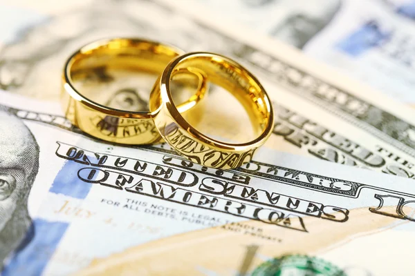 Fedi nuziali dorate sullo sfondo delle banconote. Matrimonio di convenienza — Foto Stock