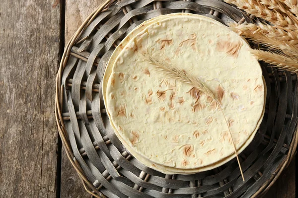 Pilha de tortilla de farinha de trigo integral caseira no tapete de vime, no fundo de madeira — Fotografia de Stock