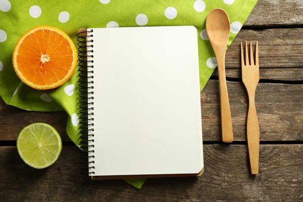 Geöffnetes Rezeptbuch, Zitronenscheiben auf farbigem Tischdecken-Hintergrund — Stockfoto