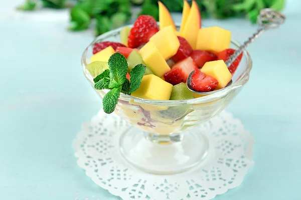 Ensalada de frutas en tazón de vidrio con menta sobre fondo de madera de color —  Fotos de Stock