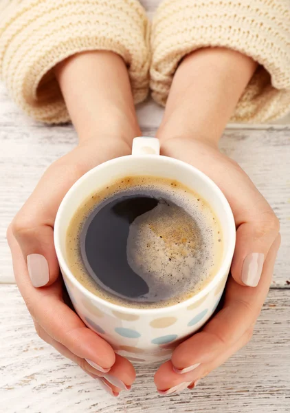 Female hands holding cup of coffee on wooden background — Stock Photo, Image