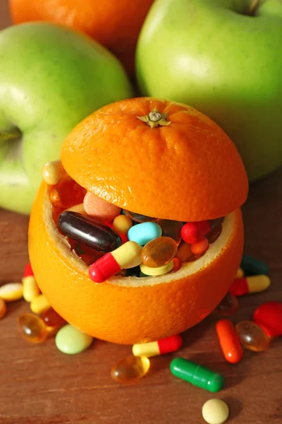 Naranja lleno de frutas coloridas píldoras, sobre fondo de madera —  Fotos de Stock