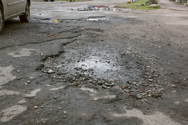 Estrada de má qualidade com buracos e poças — Fotografia de Stock