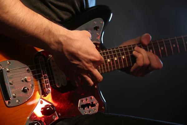 Young man playing on electric guitar on dark background — Stock Photo, Image