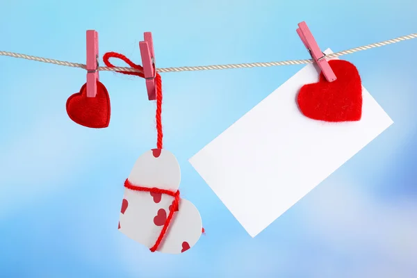 Hearts and card hanging on rope on bright background — Stock Photo, Image