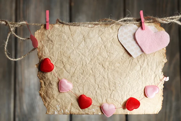 Corazones brillantes y tarjeta colgando de la cuerda sobre fondo de madera —  Fotos de Stock