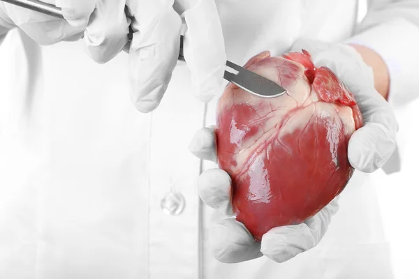 Doctor holding heart and scalpel — Stock Photo, Image