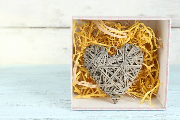 Плетеное сердце в настоящей коробке на деревянном столе — стоковое фото
