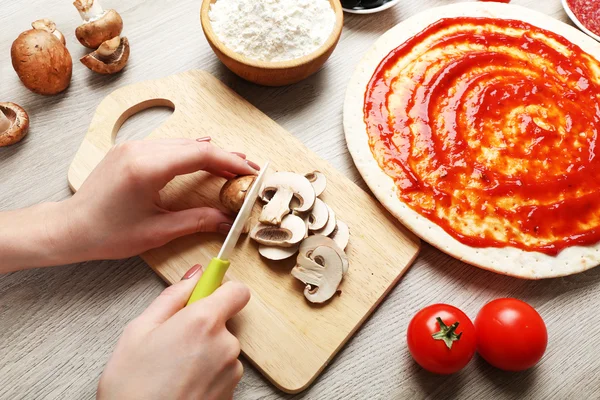 Žena ruce vaření pizza na dřevěný stůl, detail — Stock fotografie