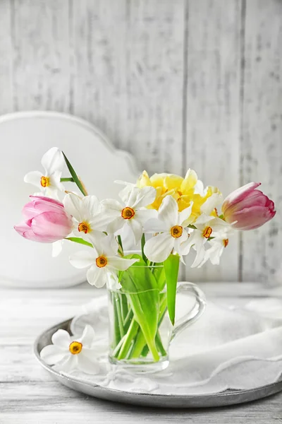 Jarní kytice ve skleněných hrnek na barevné dřevěné pozadí — Stock fotografie