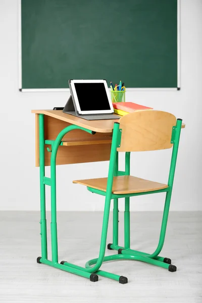 Escritorio de madera con papelería y tableta en clase —  Fotos de Stock