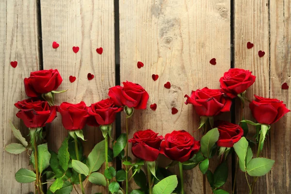 Rosas rojas sobre fondo de madera — Foto de Stock