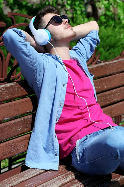 Homme avec écouteurs reposant sur le banc — Photo