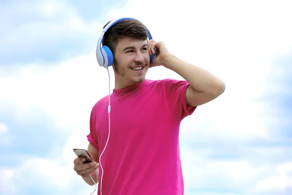 Man met hoofdtelefoon over blauwe hemel — Stockfoto
