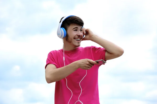 Homme avec écouteurs sur ciel bleu — Photo