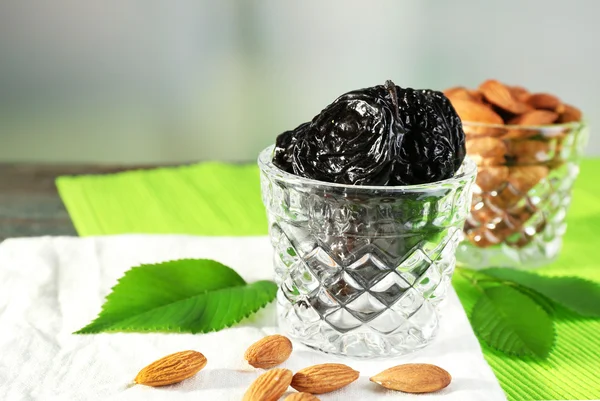 Ciruelas pasas y almendras en vasos con hojas en servilleta verde, primer plano — Foto de Stock