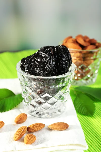 Prunes and almonds in glasses with leaves on green napkin, closeup — Stock Photo, Image