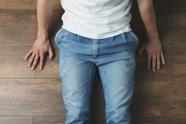 Hombre joven sentado en el suelo de madera en la habitación — Foto de Stock