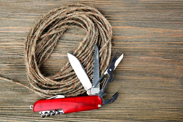 Карманный нож с веревкой на деревянном столе — стоковое фото
