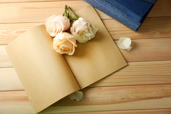 Fresh roses on old notebook, on wooden table background — Stock Photo, Image