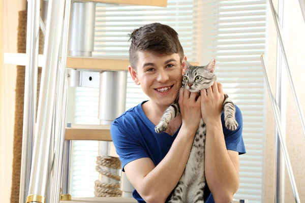 Handsome young man with cute cat sitting on steps at home — Stock Photo, Image