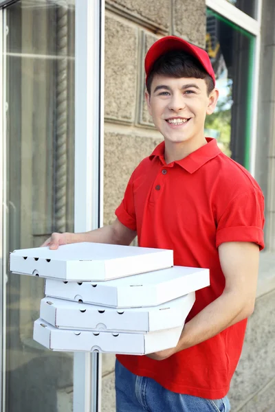 Jeune homme livrant une boîte à pizza près de la maison — Photo