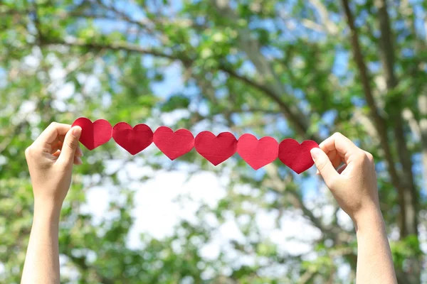 Manos femeninas con cadena de corazones de papel —  Fotos de Stock