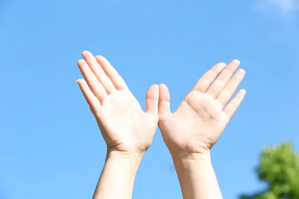 Vrouwelijke handen over blauwe hemel — Stockfoto