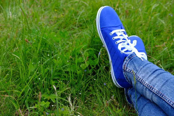 Vrouwelijke voeten in gumshoes op groen gras — Stockfoto