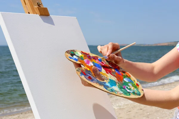 Palette and easel with canvas on beach — Stock Photo, Image