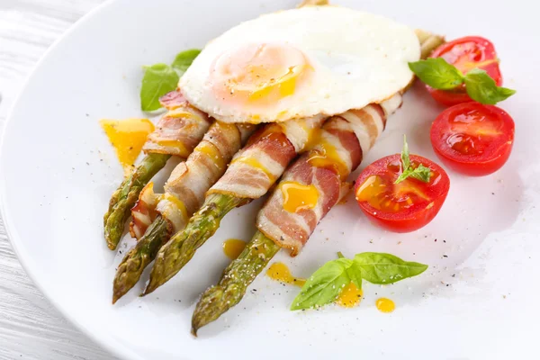 Piatto di asparagi con pancetta e uovo in piatto sul tavolo, primo piano — Foto Stock