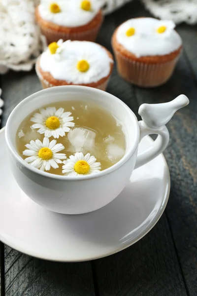 Rumianek herbatę z kwiatów rumianku i smaczne babeczki na kolor drewniane tła — Zdjęcie stockowe