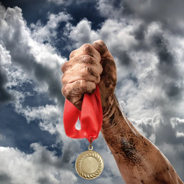 Golden medal in dirty hand on sky background — Stock Photo, Image