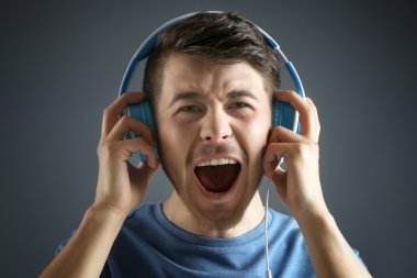 yakışıklı genç adam gri arka planda müzik dinlemek